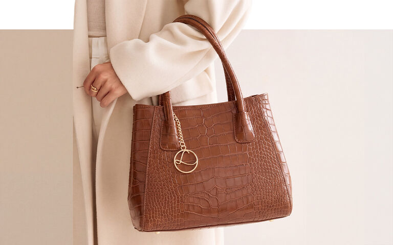 Braune Handtasche am Arm einer Frau